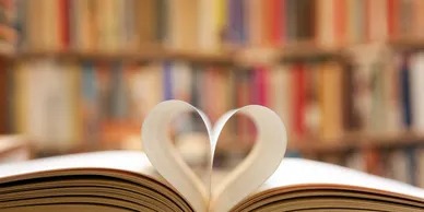 A Book With a Heart Shape on Its Cover Placed in Front of a Library Building, Symbolizing Love for Reading.