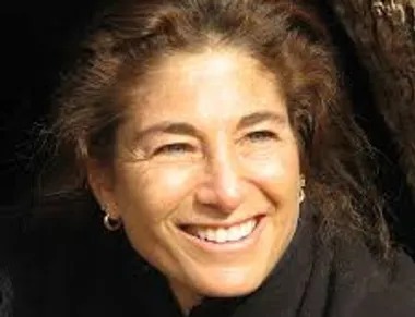 A Woman Smiles While Sitting Comfortably in the Branches of a Tree, Surrounded by Green Leaves.